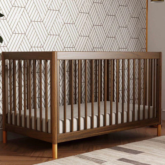 Natural walnut convertible crib with gold feet for Los Angeles nurseries.