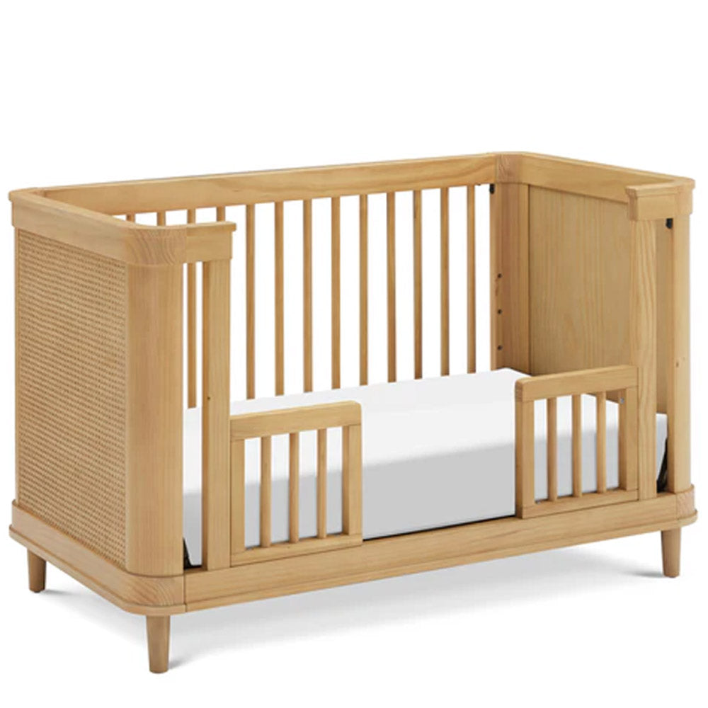 Side view of honey finish Marin convertible crib with cane accents, a warm and modern baby bed for Los Angeles homes.
