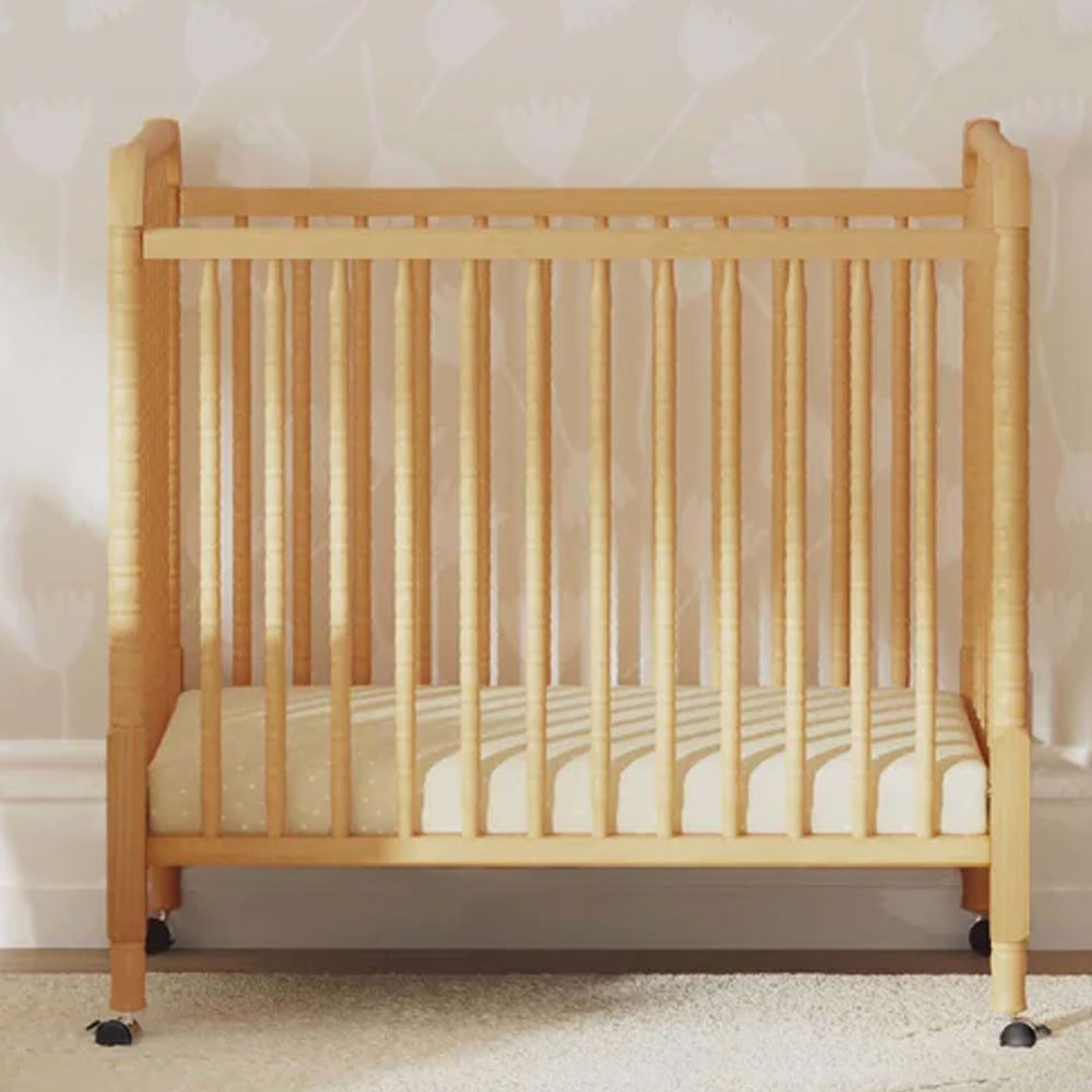 Space-saving Jenny Lind mini crib with classic spindle design for nurseries in Los Angeles.