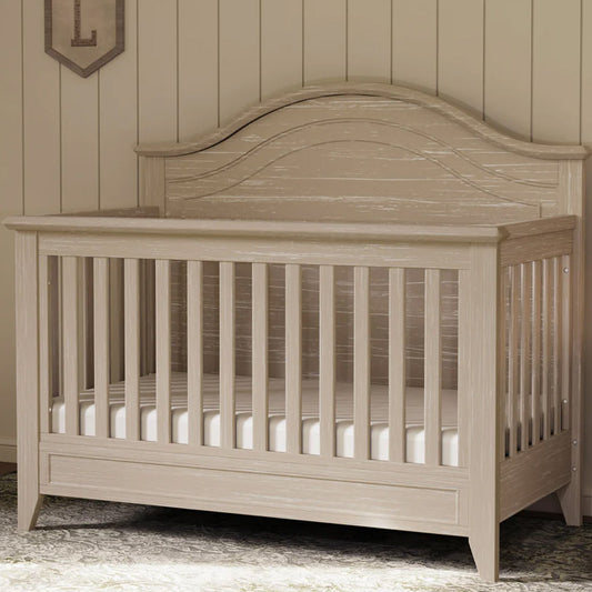 Rustic curve-top convertible crib with adjustable mattress heights in nursery setting

